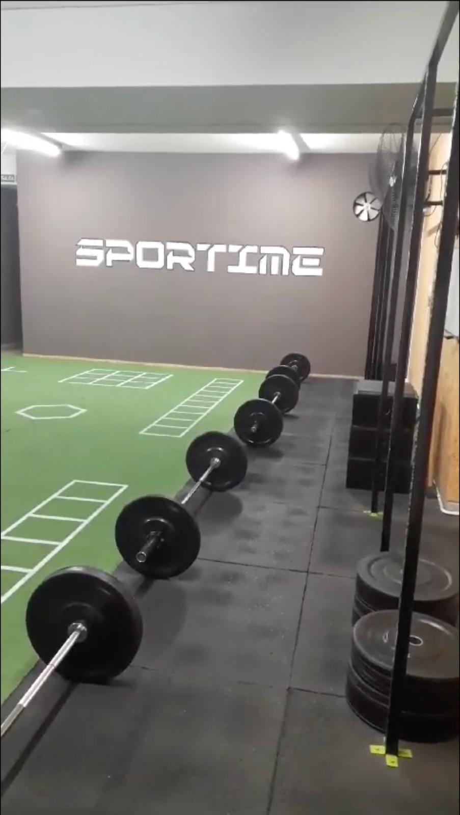 Functional training gym floor with kettlebells, dumbbells on rack, black rubber flooring, modern athletic gym in Buenos Aires, clean well-lit fitness equipment area
